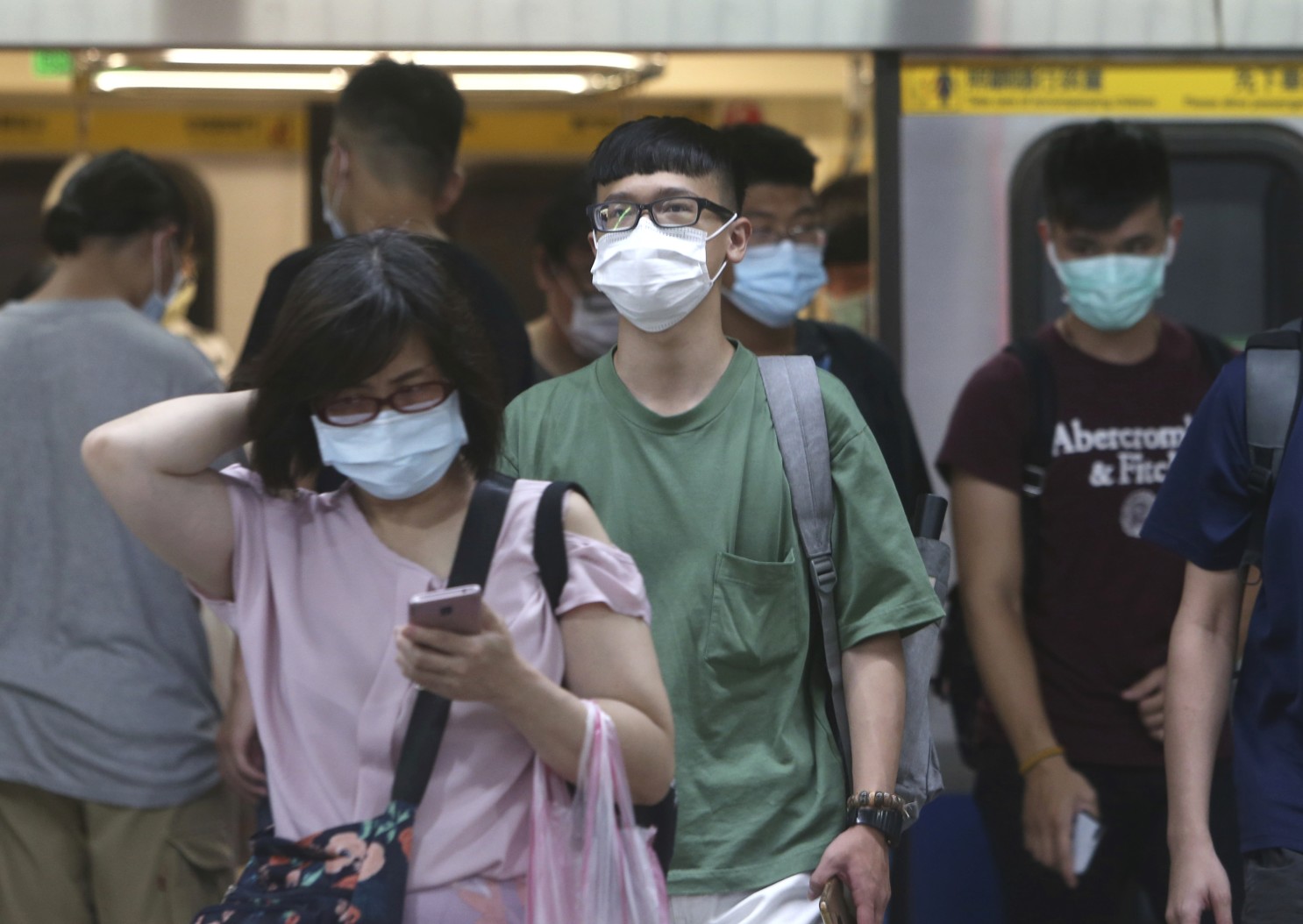 asians wearing masks at a train station