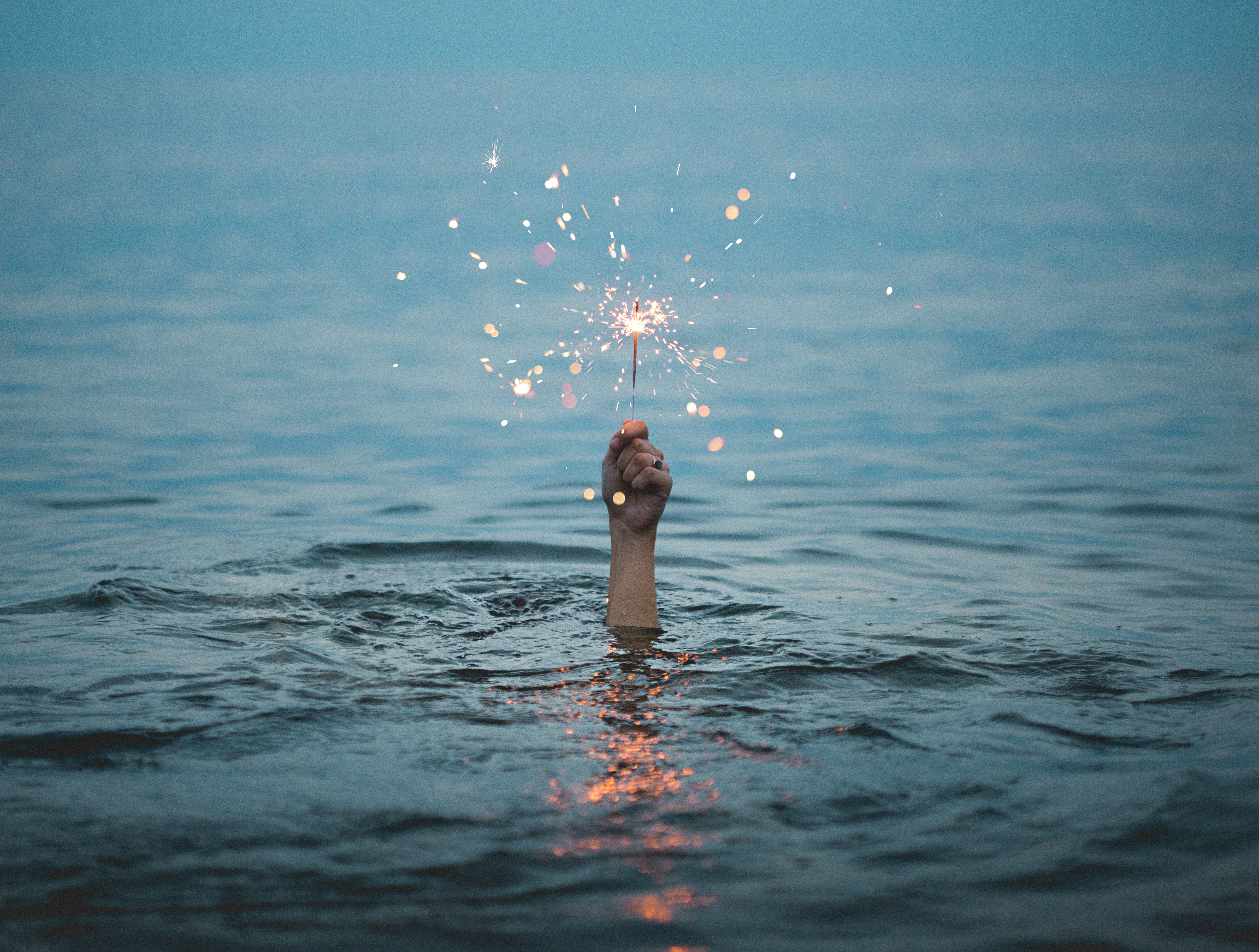 a hand holding a sparkle in the midst of the ocean