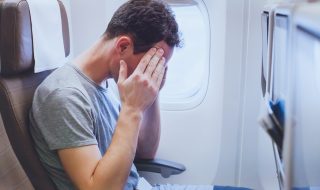 Man holding his head on the plane