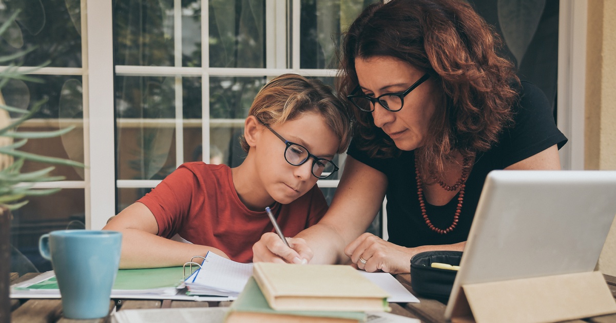 a parent writing while a child looks on