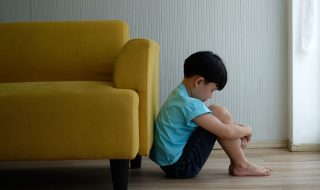 a sad boy leaning against the sofa