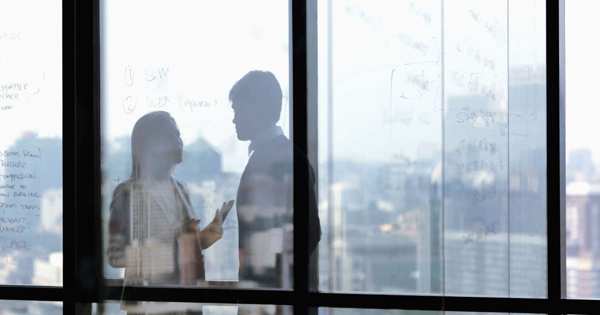 colleagues talking behind a glass door