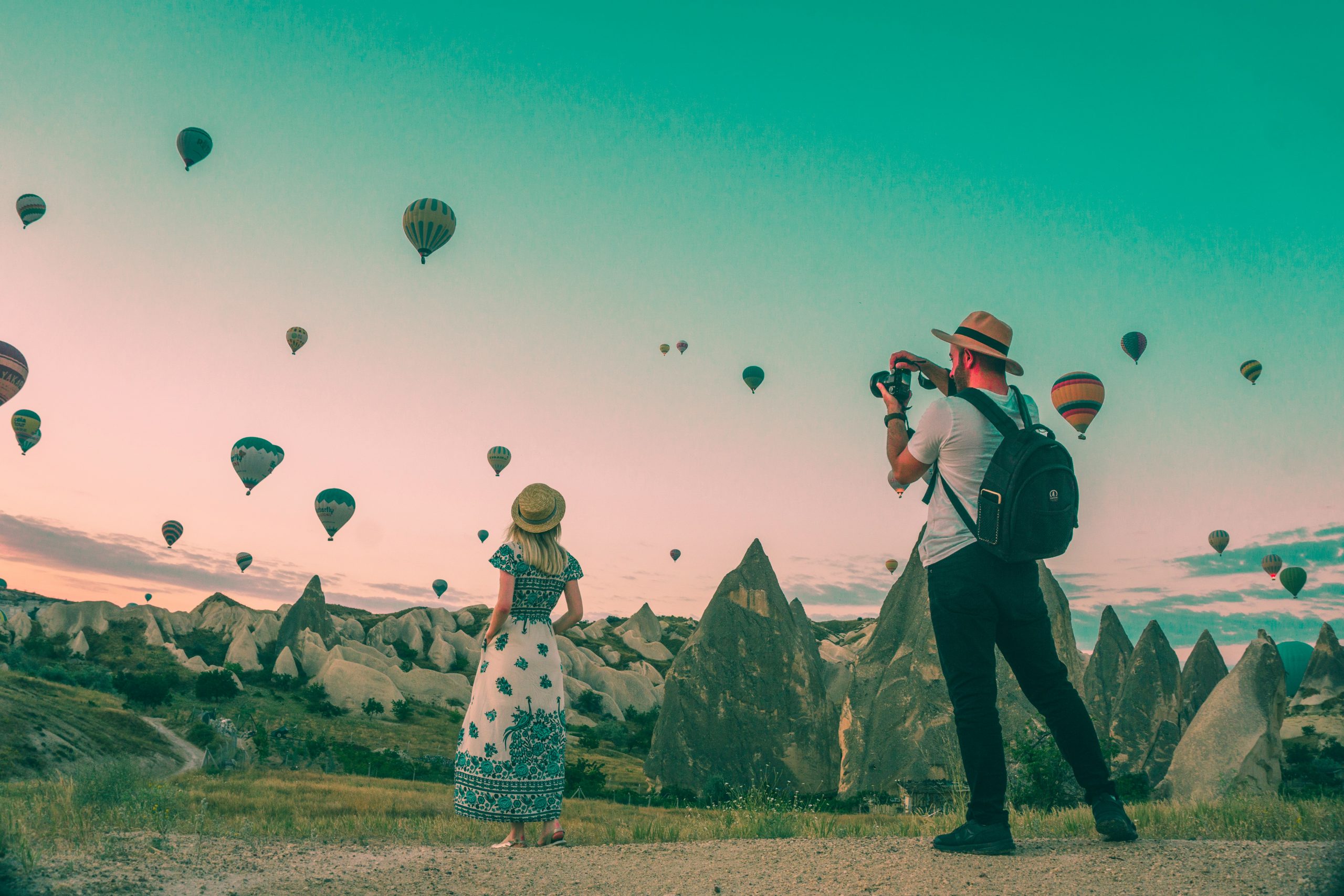 man taking photo of woman against a backdrop of hot air balloons