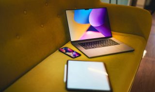 a laptop, phone, and tablet on a sofa