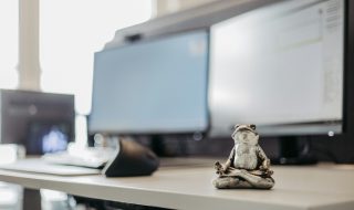 a frog statue on a work desk