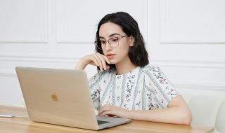 a young lady sitting in front of a MacBook