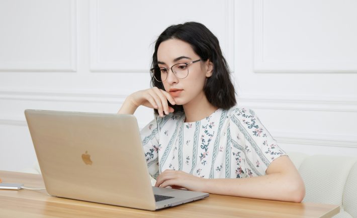 a young lady sitting in front of a MacBook