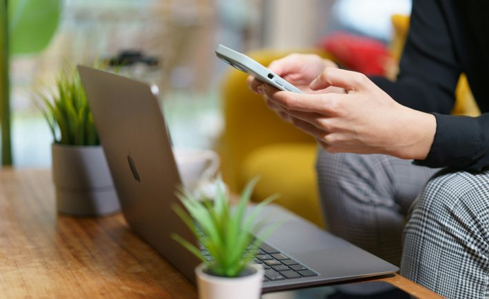 a person using a phone in front of a laptop