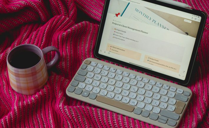 an ipad, keyboard, and cup on a red blanket